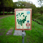 A hole sign displaying basic disc golf rules for beginners to read.