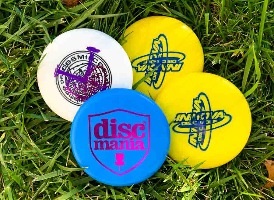 A photo of four mini disc golf discs on grass